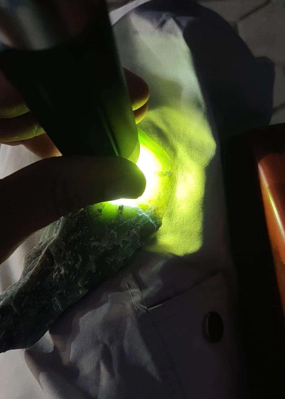 A torch pressed to rough Hilal Abad nephrite. Light travelling through the stone is the first sign buyers look for.